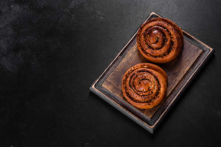 Freshly baked cinnamon roll with spices and cocoa filling on a black background. Cinnabon buns. Swedish breakfast.の写真素材