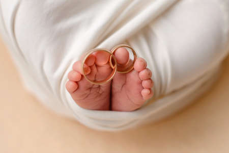 Little feet of a newborn baby with his parents' wedding rings on his fingers. Family traditionsの写真素材