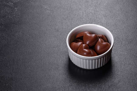 Sweet delicious sweets in the form of chocolate hearts in a white saucer. Celebrating Valentine's Dayの写真素材