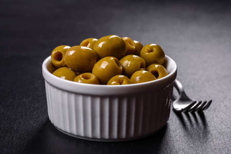 Beautiful pickled green olives on a dark concrete background. Preparation of the festive tableの写真素材