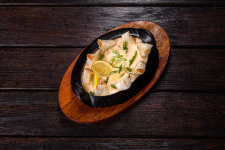 A delicious seafood dish baked with cheese and breadcrumbs in a cast iron bowl with spices and herbsの写真素材