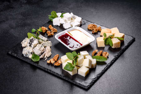 Several types of cheese on a shale tray with mint and sweet sauces. Snacks to the festive tableの写真素材