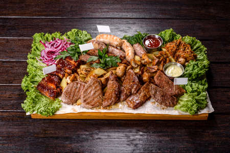 Several types of roasted meat with spices and herbs on a wooden tray. Preparing a Table for a Big Companyの写真素材