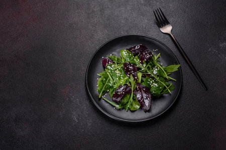 Fresh delicious salad with sleeves, spinach and beet leaves with olive oil on a black plate. Tasty...