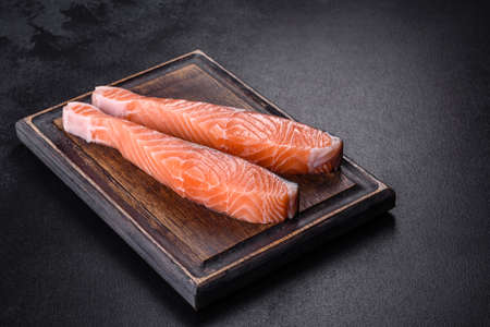 Salmon. Fresh raw salmon fish fillet with cooking ingredients and herbs on black backgroundの写真素材