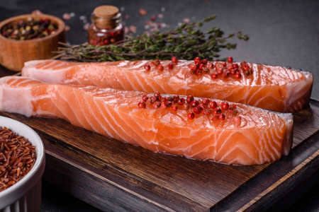 Salmon. Fresh raw salmon fish fillet with cooking ingredients and herbs on black backgroundの写真素材