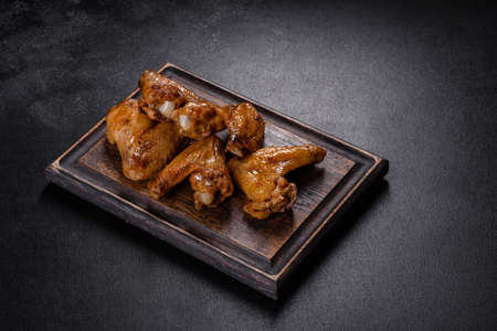 Crispy barbecue chicken wings with vegetables and spices on a black backgroundの写真素材