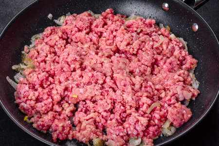Fresh raw beef mince with onions in a pan. Cooking tasty healthy foodの写真素材