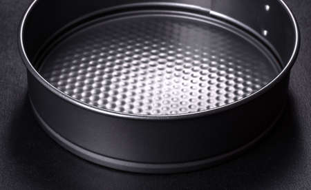 Round cake pan, tray or mould on a black concrete background. Cooking at home