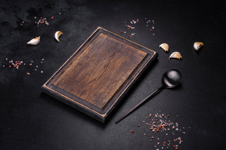 Black metal spoon and rectangular cutting board on black concrete background. Preparing for Cooking