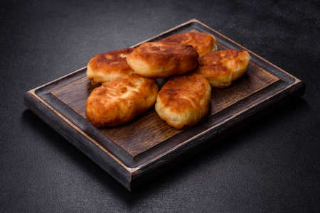 Delicious homemade pies with potatoes on a dark concrete background. Home cooked pastries