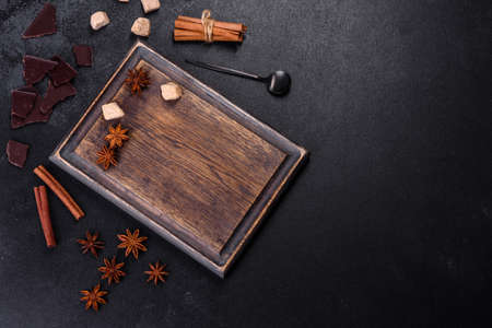 Sugar, cinnamon and other spices on a wooden cutting board on a dark concrete backgroundの写真素材