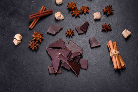 Broken black chocolate pieces with star anise and cinnamon on black backgroundの写真素材