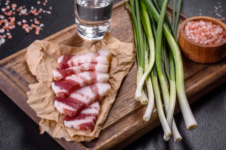 Fresh delicious pork lard with green onions on a wooden cutting board on a dark concrete backgroundの写真素材