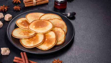 Delicious fresh pancakes on a wooden cutting board with sugar on a dark concrete background