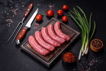 Raw barbecue sausages with spices and vegetables. Free space for your textの写真素材