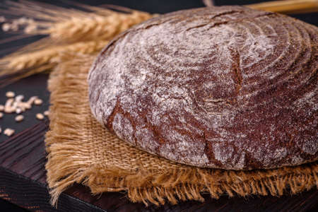 Brown fresh bread with seeds on a dark concrete background. Top view, copy spaceの写真素材