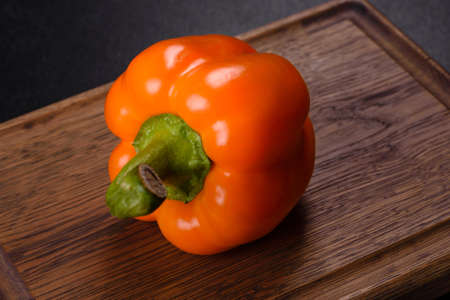 Fresh beautiful bell pepper orange on a dark concrete background. Cooking vegitarian food at home