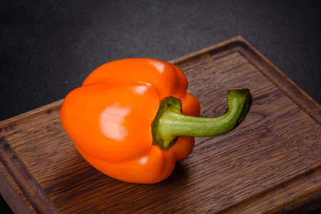 Fresh beautiful bell pepper orange on a dark concrete background. Cooking vegitarian food at home