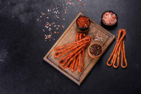 Delicious fresh bright smoked hot sausages with cherry tomatoes on a dark concrete tableの写真素材