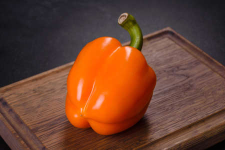 Fresh beautiful bell pepper orange on a dark concrete background. Cooking vegitarian food at homeの写真素材
