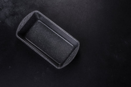 An empty ceramic grey baking dish on a dark concrete background. Preparation for baking tasty cupcakeの写真素材