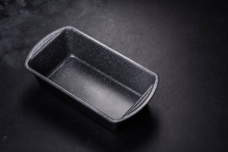 An empty ceramic grey baking dish on a dark concrete background. Preparation for baking tasty cupcakeの写真素材