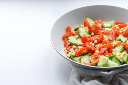 A delicious salad with beans, tomatoes and cucumbers on a white background. Making a delicious healthy breakfastの写真素材