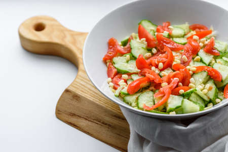 A delicious salad with beans, tomatoes and cucumbers on a white background. Making a delicious...