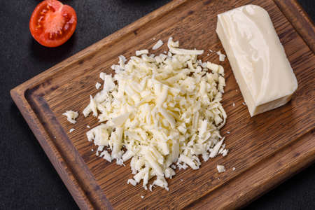 Block of mozzarella cheese and pieces on wooden cutting board