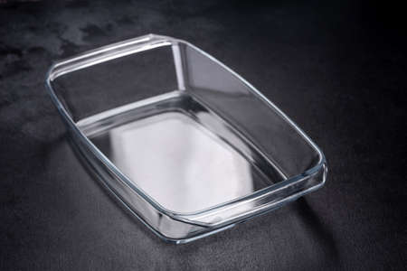 A rectangular glass empty dish for baking on a dark concrete background. Preparation for baking...