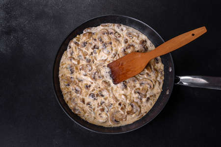 Delicious fresh young champignons sliced into slices in creamy sauce simmered in a black panの写真素材