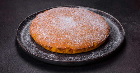 Pumpkin pie with whipped cream and cinnamon on a dark background, top view