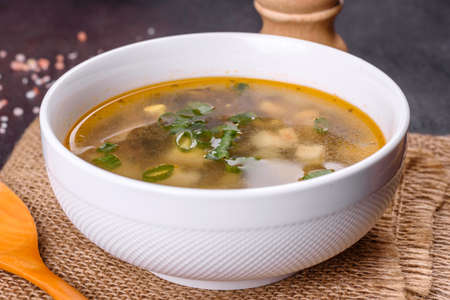 Delicious healthy soup with sorrel, tomato, potatoes, spices and herbs in a white bowl against a dark concrete background. Vegetarian dishの写真素材
