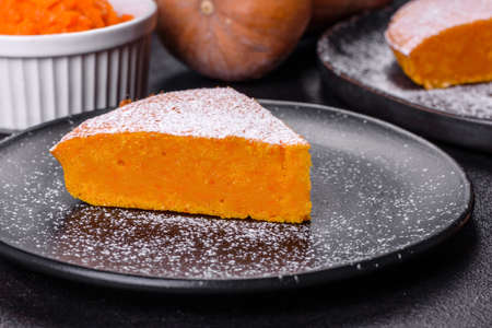 Pumpkin pie with whipped cream and cinnamon on a dark background, top view