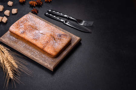 Baked rectangular cupcake with raisins and chocolate on a dark concrete background. Homemade...