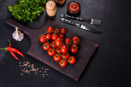 Fresh cherry tomatoes on a black background with spices. Food backgroundの写真素材