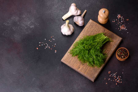 A bunch of fresh green dill on a wooden cutting board on a dark concrete background. Cooking at homeの写真素材