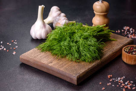 A bunch of fresh green dill on a wooden cutting board on a dark concrete background. Cooking at homeの写真素材