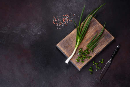 Cut Green onions chives on a cutting board. Dark concrete backgroundの写真素材