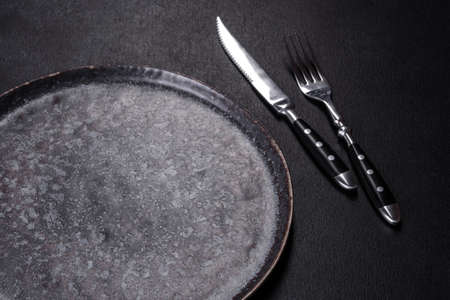 Empty black plates, fork and knife on a black background. Top view, copy space