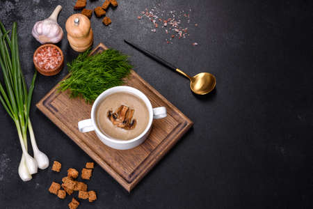 A delicious fresh, thick soup of mushroom puree with breadcrumbs, spices and herbs on a wooden board...