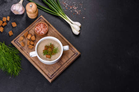 A delicious fresh, thick soup of mushroom puree with breadcrumbs, spices and herbs on a wooden board against a dark concrete background. Vegetarian cuisineの写真素材