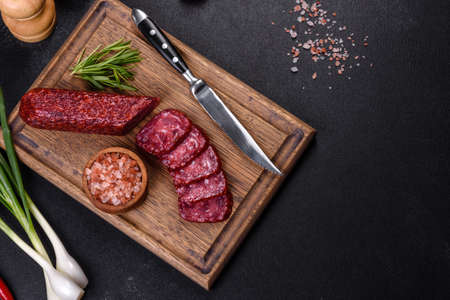 Salami with fresh rosemary and spices. On a black stone backgroundの写真素材