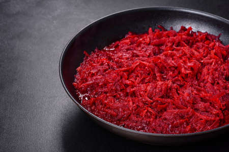 Chopped beetroot in a pan as well as spices and herbs on a wooden cutting board as ingredients in the preparation of traditional Ukrainian borschtの写真素材