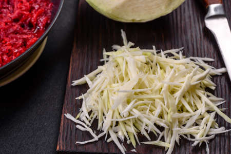 Chopped beetroot in a pan as well as spices and herbs on a wooden cutting board as ingredients in the preparation of traditional Ukrainian borschtの写真素材