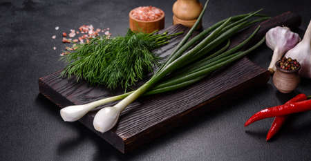 Spring onions, dill, garlic and hot pepper as well as spices and herbs on a wooden cutting board as ingredients in the preparation of traditional Ukrainian borschtの写真素材