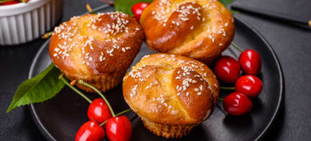 Bunch of freshly baked cherry muffins with fresh berries on a rustic concrete table