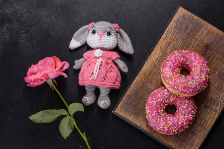 A beautiful doughnut with pink glaze and colored sprinkle on a dark concrete background. Sweets to the dinner tableの写真素材