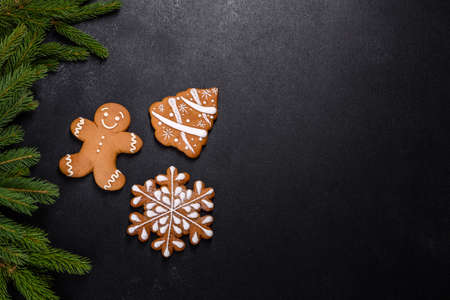 Beautiful delicious gingerbread gingerbread with Christmas tree branches on a dark concrete background. Preparing decorations for the Christmas tableの写真素材